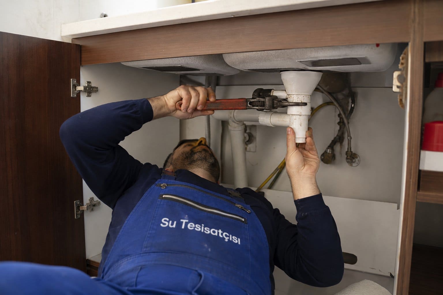 Lavabo altında boru tamiri yapan tesisatçı